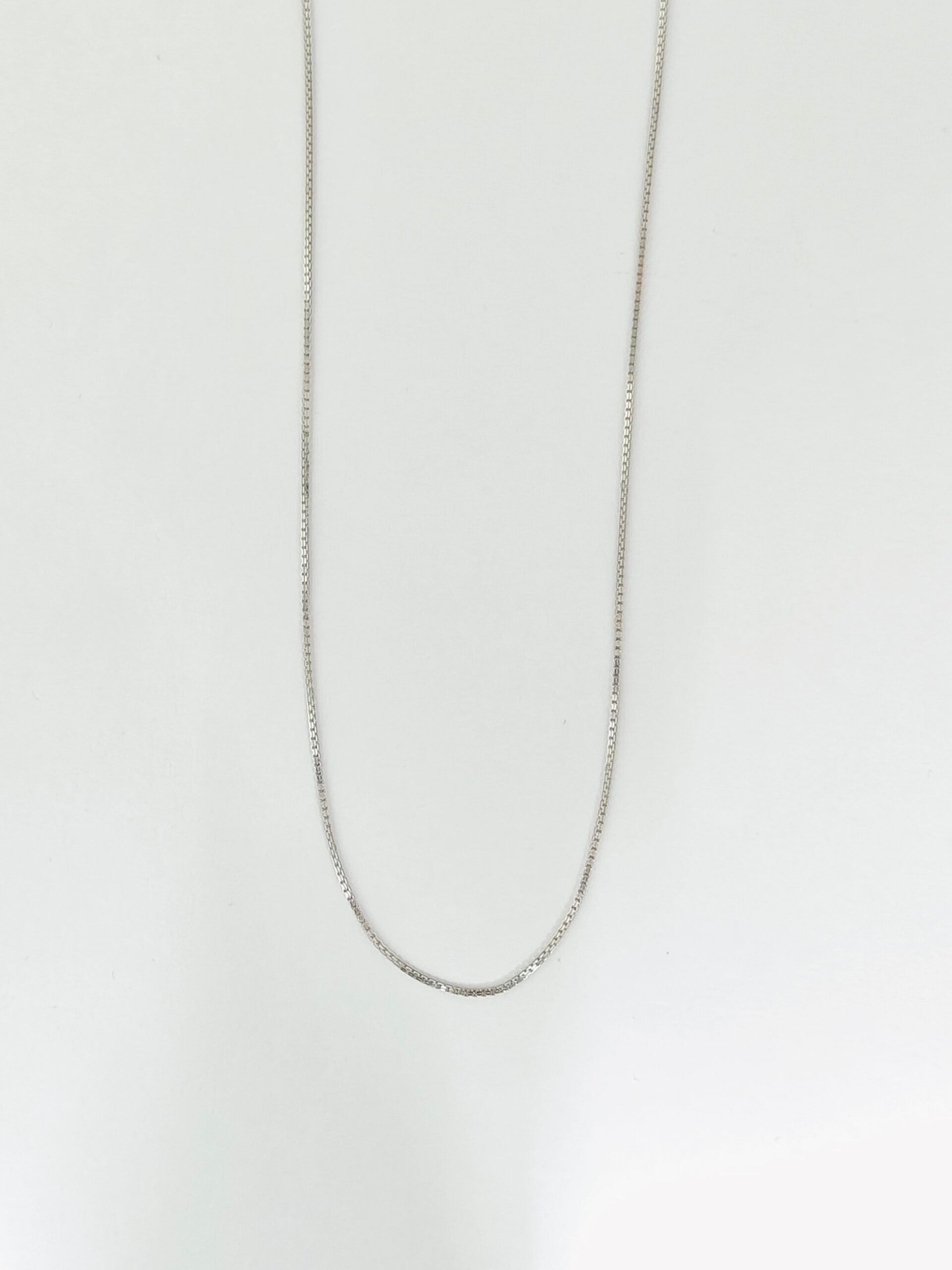Silver chain necklace on a light gray background